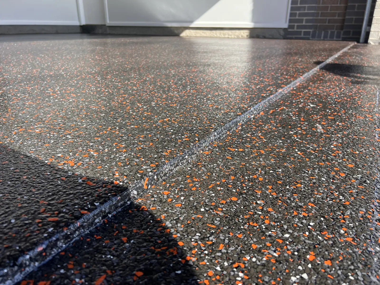 Black and orange decorative flake coating on a garage entry and steps